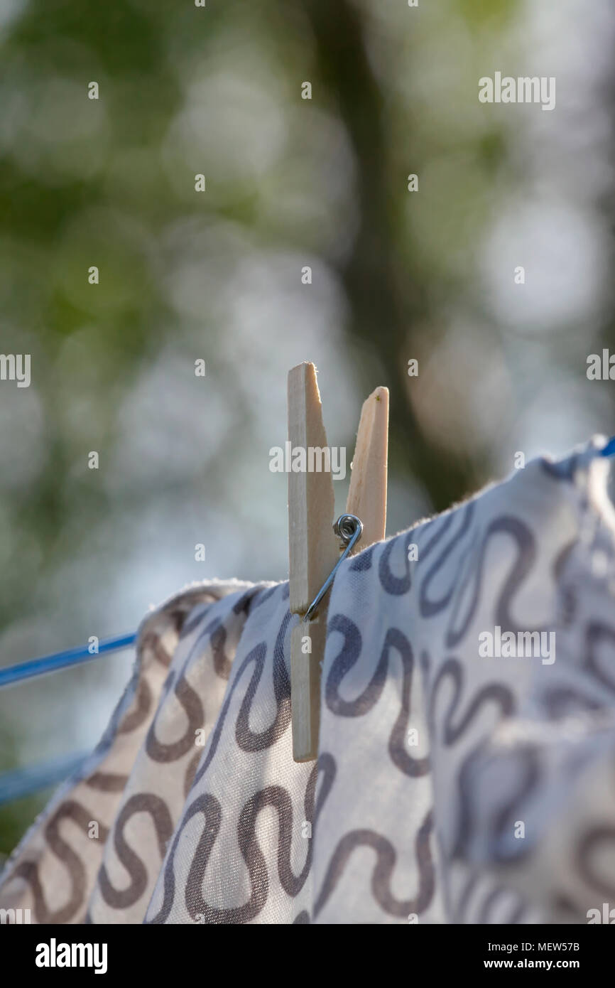 Close up of clothes pegs securing washing hanging to dry in a garden on a sunny summer day. Stock Photo
