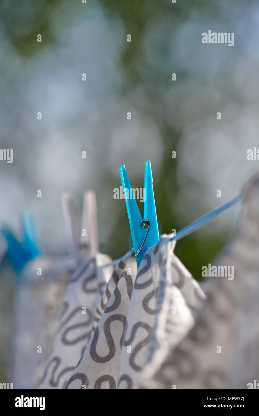 Close up of clothes pegs securing washing hanging to dry in a garden on a sunny summer day. Stock Photo