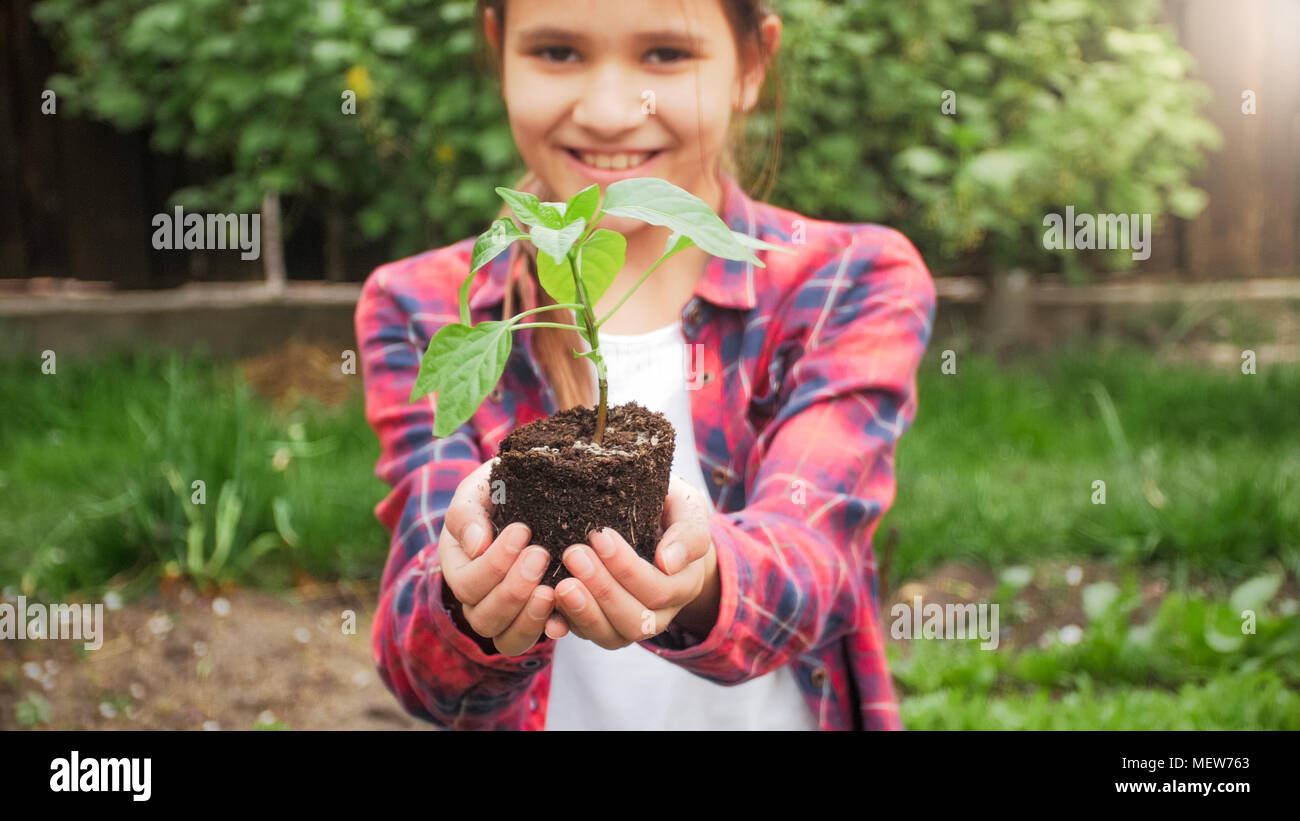 Portrait of smiling cute girl posing with seedling in hands Stock Photo