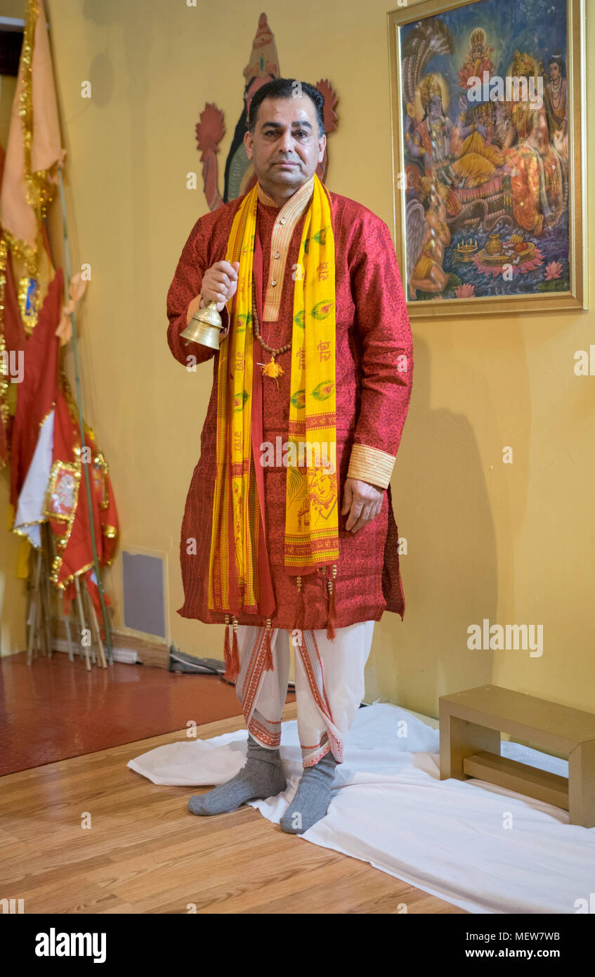 Portrait of a Hindu priest or pundit, ringing a bell during services at the Shri Lakshmi Narayan Mandir  temple in Richmond Hill, Queens, New York. Stock Photo