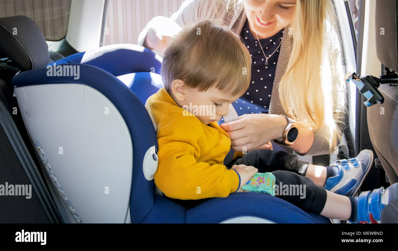 Closeup photo of mother seating her son in car safety seat Stock Photo ...
