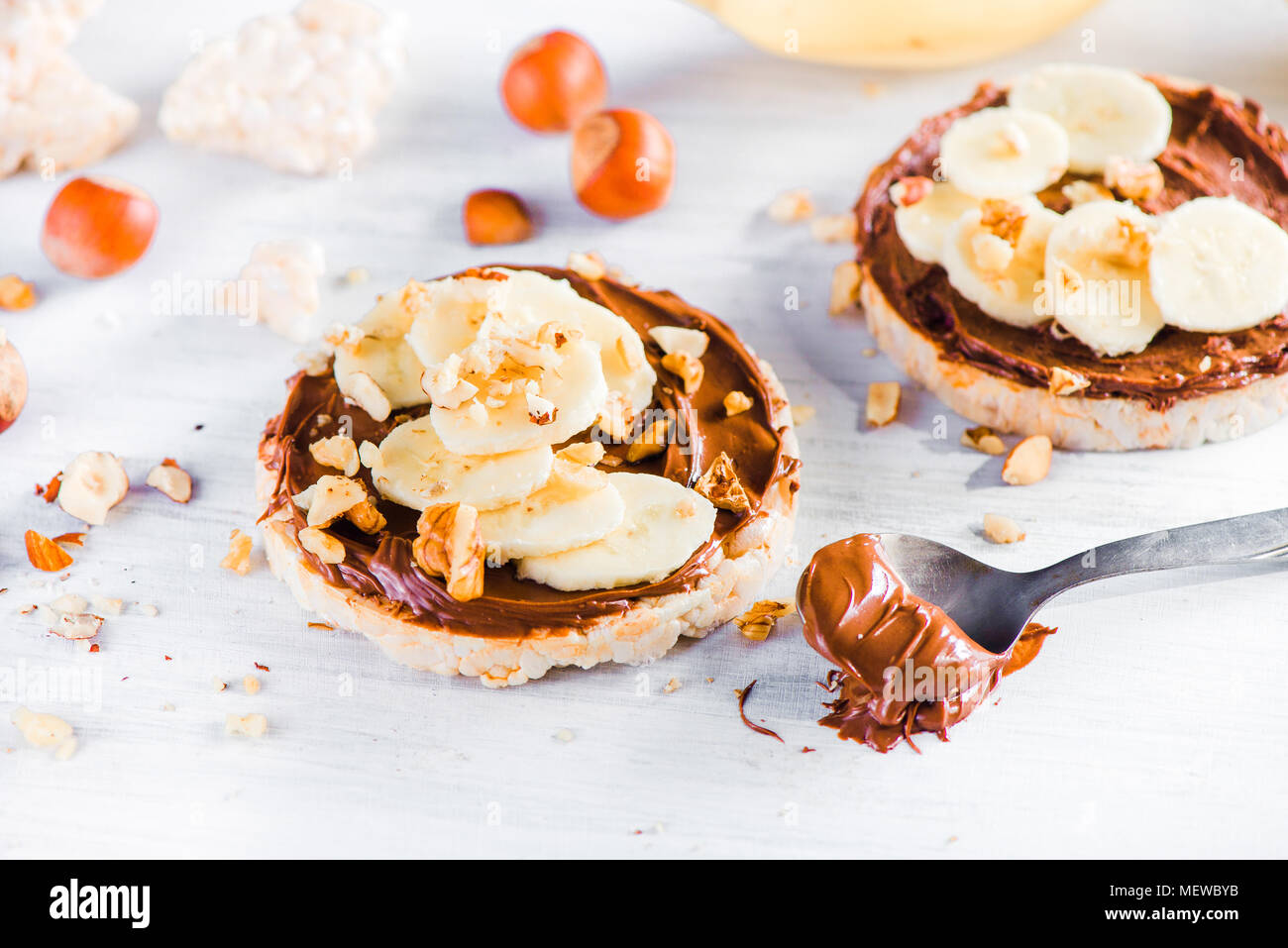 Crisp bread banana and chocolate snack. Healthy breakfast with hazel nuts. High key diet concept. Stock Photo
