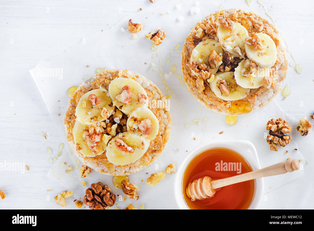 Crisp bread banana and peanut butter snack. Healthy breakfast with walnuts and honey. High key diet concept. Stock Photo