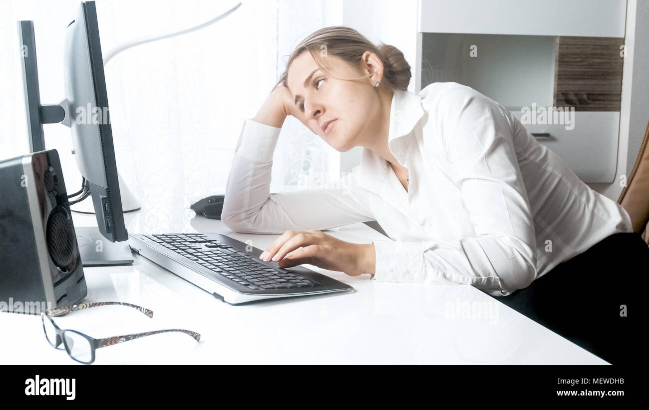 Portrait of sleepy young woman looking at computer monitor Stock Photo ...