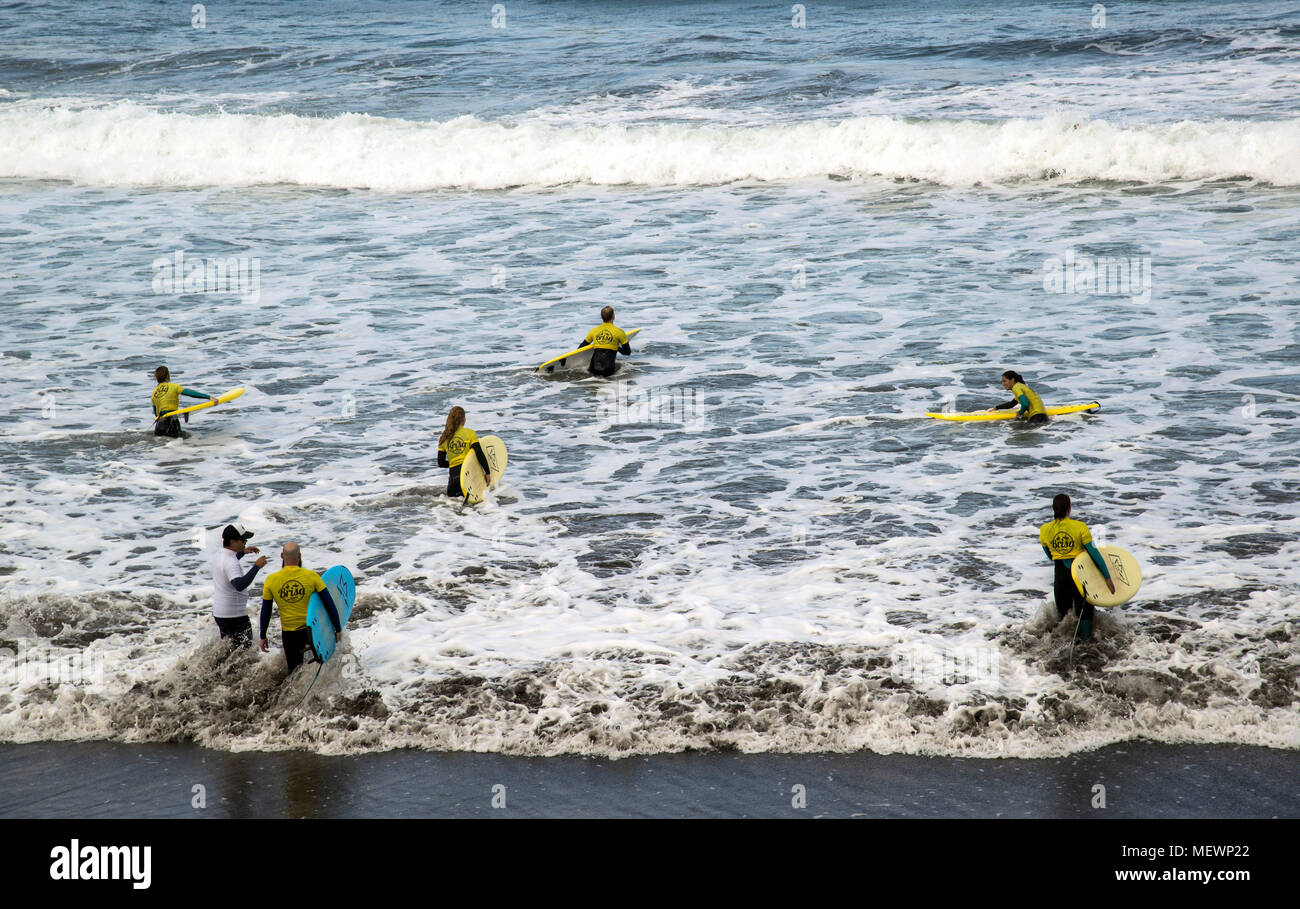 Surfers in a surfer school class on the Las Canteras beach in December in Las Palmas are  going into the water Stock Photo