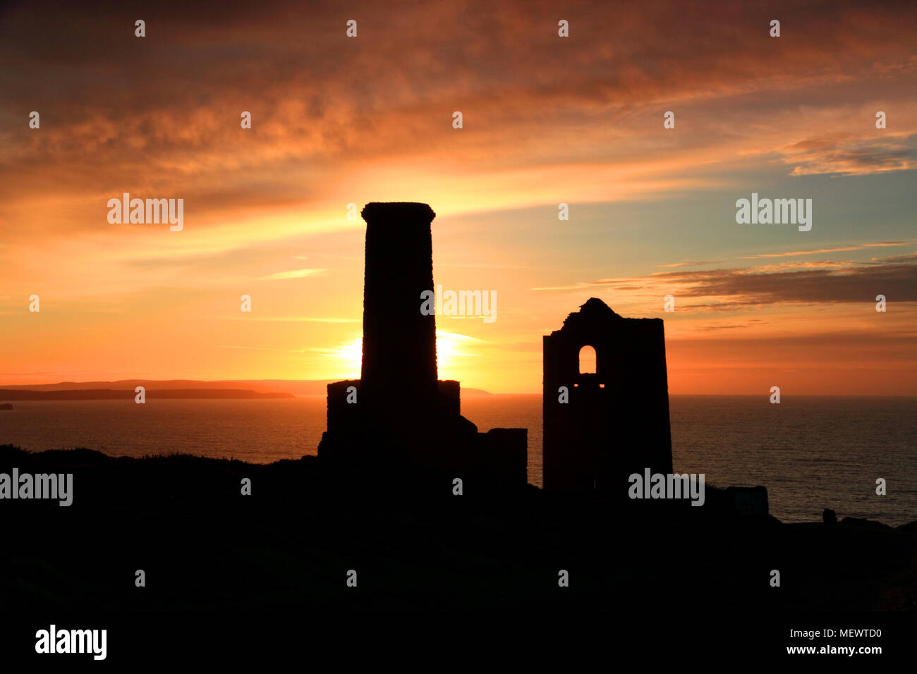 The ruins of the Towanroath engine house, St Agnes, are silhouetted by the setting sun. Stock Photo