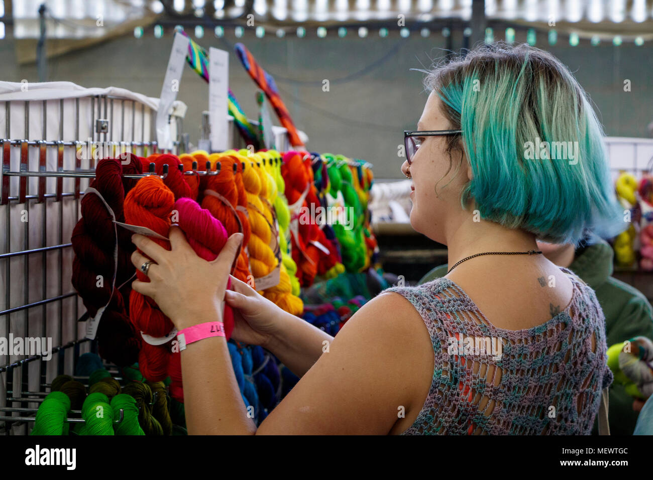 Woman with turquoise coloured hair, handles the bright and colourful woollen skeins at Yarndale, Skipton, North Yorkshire, UK. Stock Photo