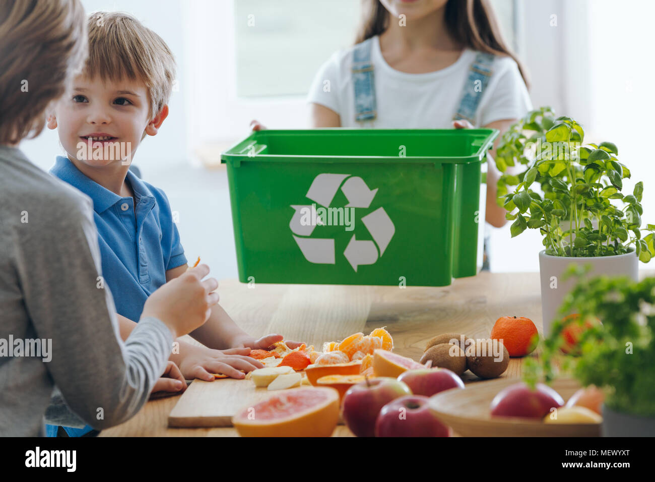 Kids in the kitchen throwing out fruit remains into a green bin for