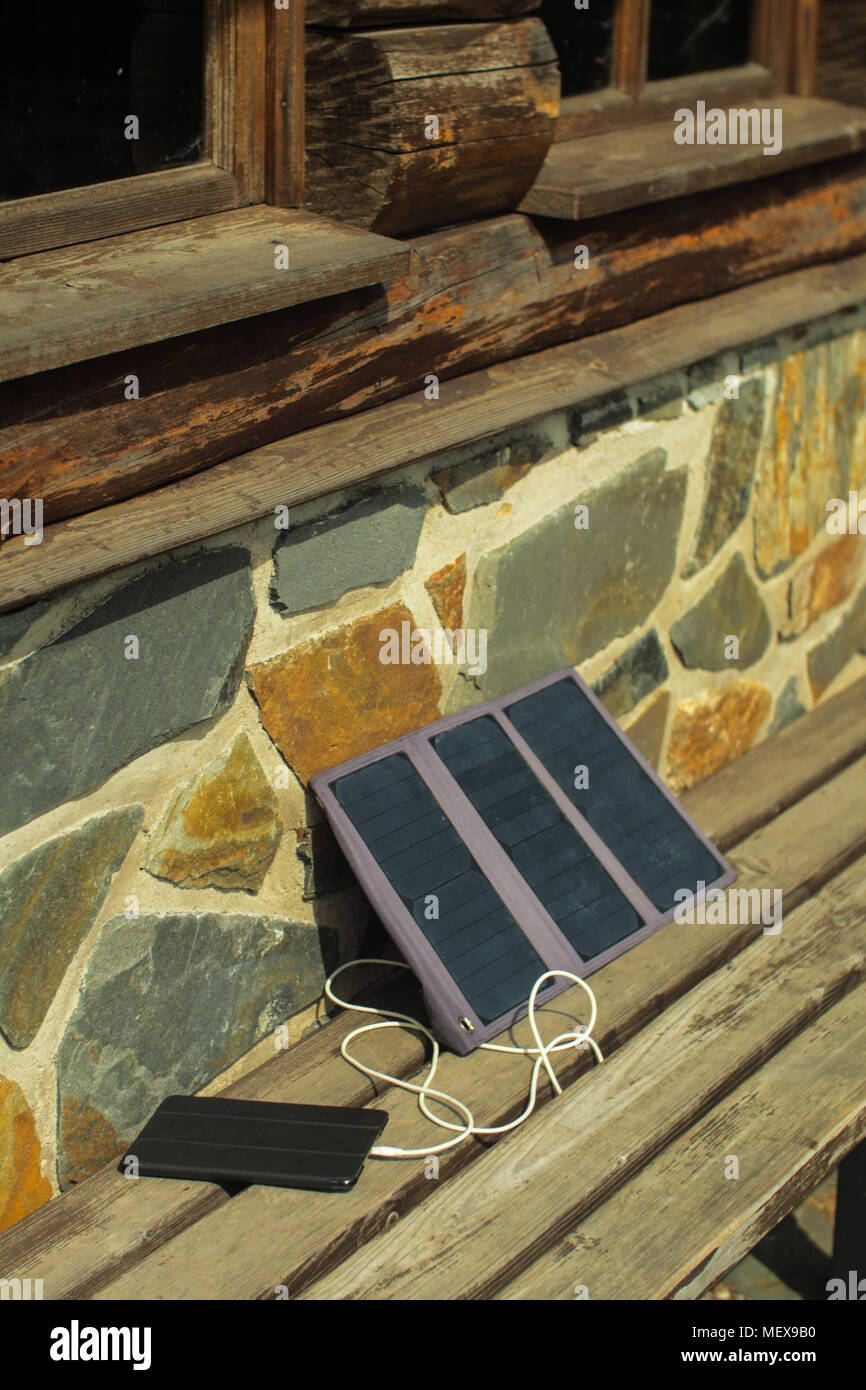 Small Solar Panel Charging A Tablet From A Sun Just Outside Of A