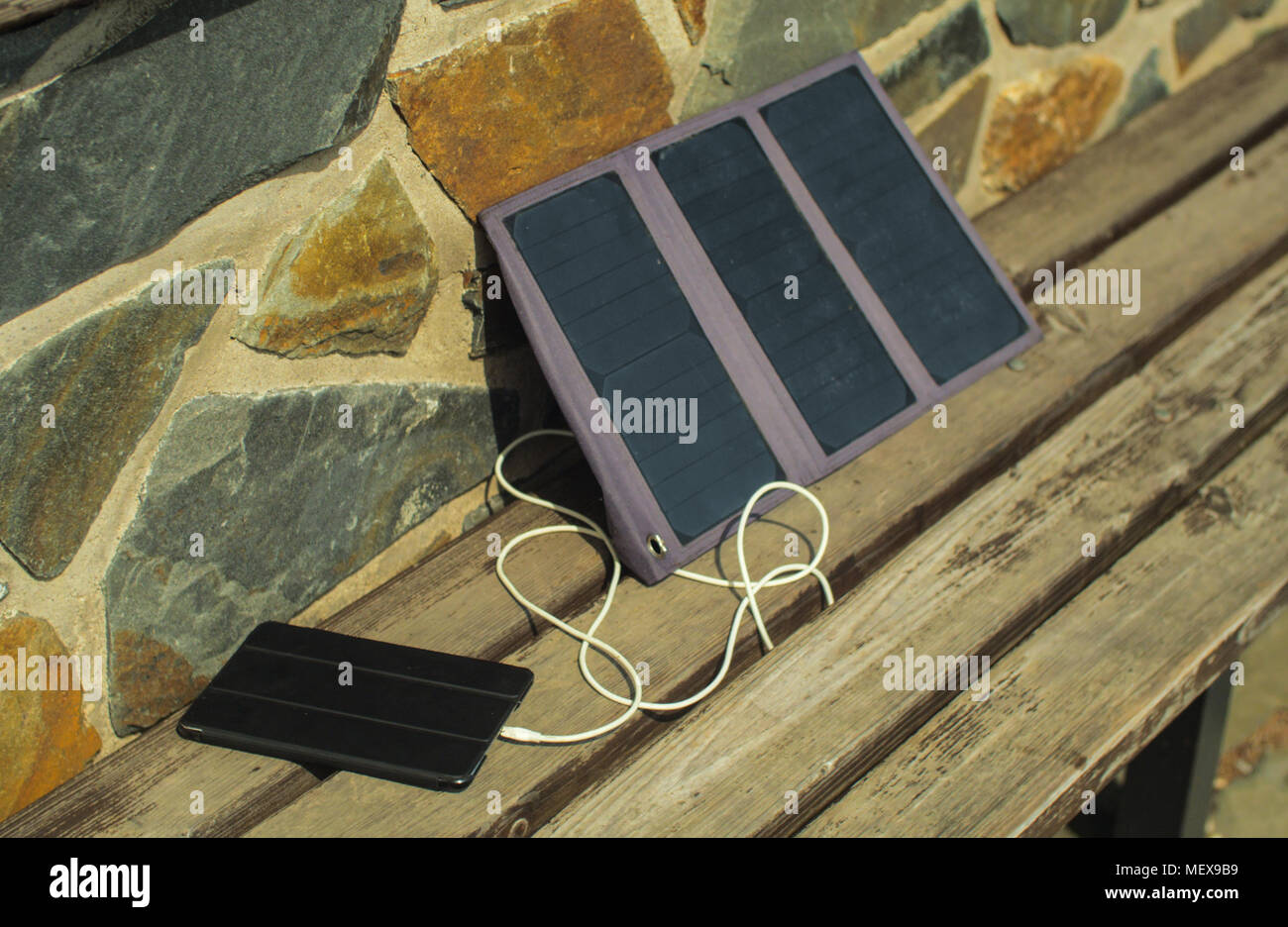 Small Solar Panel Charging A Tablet From A Sun Just Outside Of A