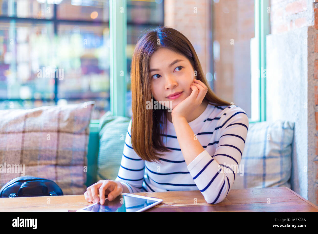 Happy young attractive asian woman relaxing by the window at a coffee ...