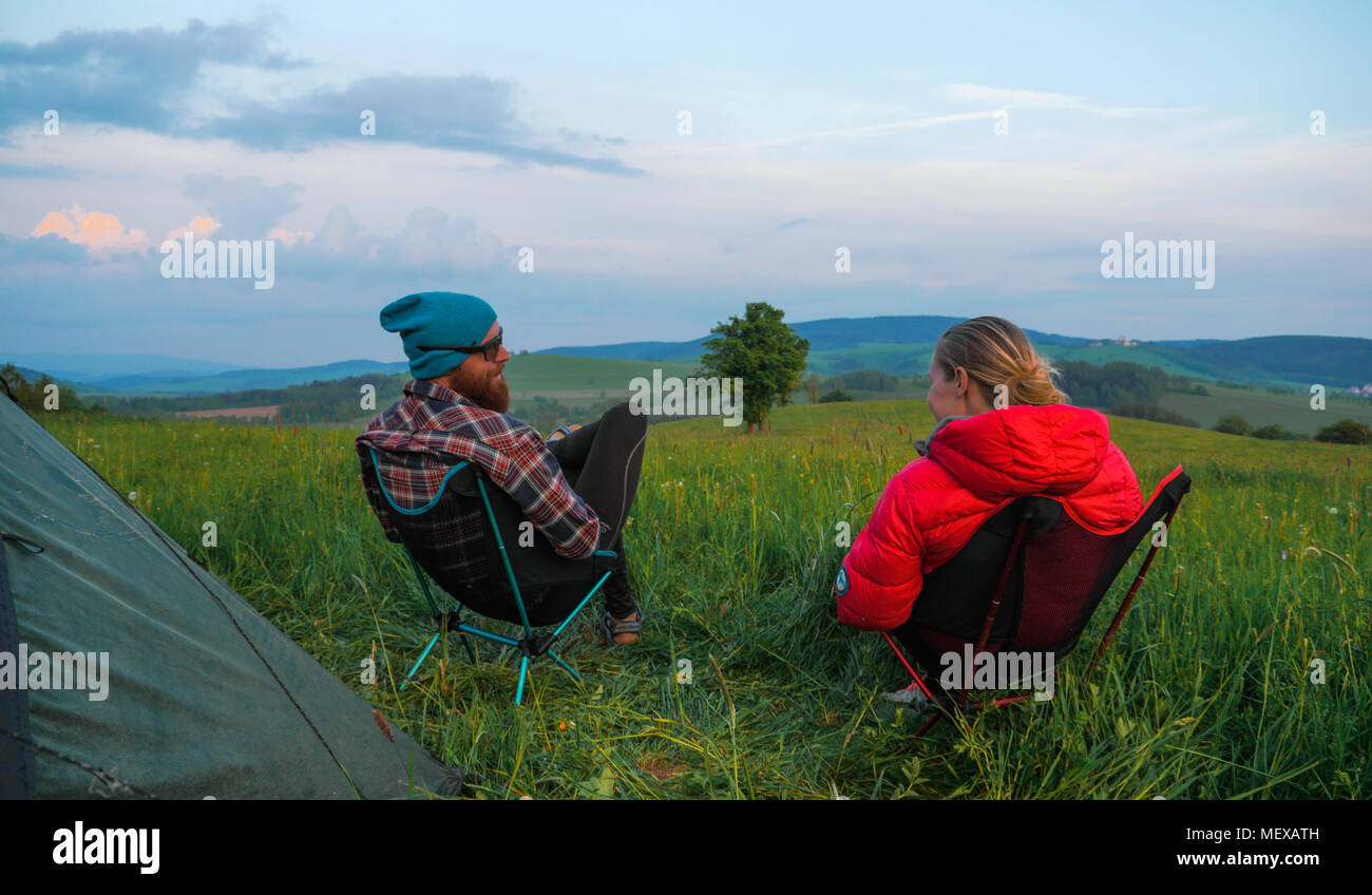 outdoors couple (man and woman) sitting in front of a tent on camping ...