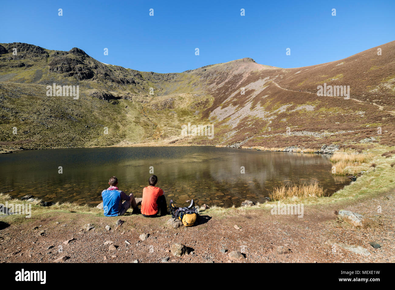 Hikers Taking a Break at Bleaberry Tarn with the View Towards Red Pike on a Hot Sunny Day, Buttermere, Lake District, Cumbria, UK Stock Photo