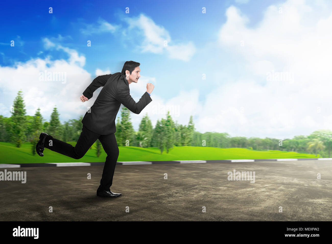 Young asian businessman in formal suit running on the road Stock Photo