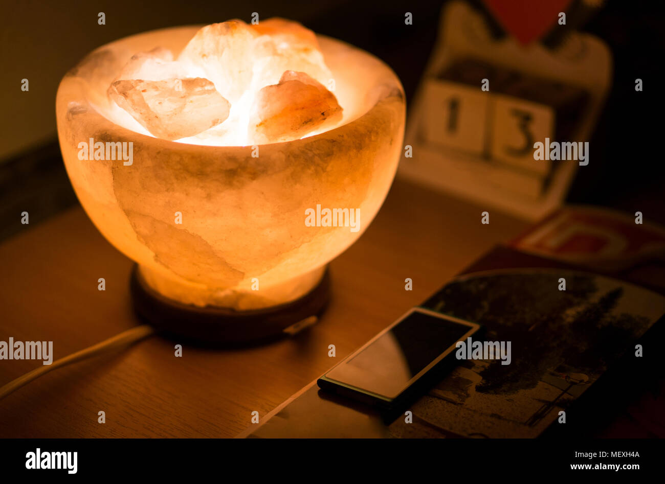 Salt lamp on the wooden table illuminatig the calendar and mp3 player. Shot on friday the 13th Stock Photo