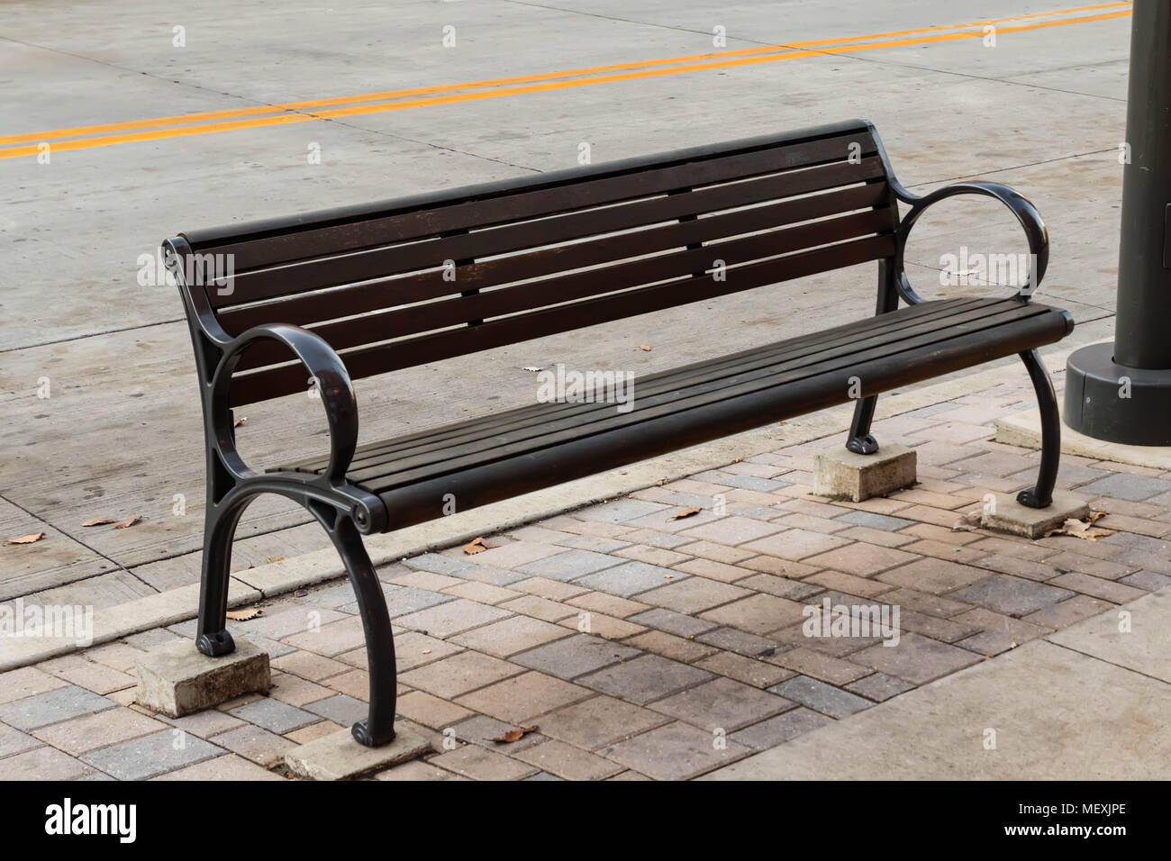 a bench just off a busy street for tired folks who live dangerously Stock Photo