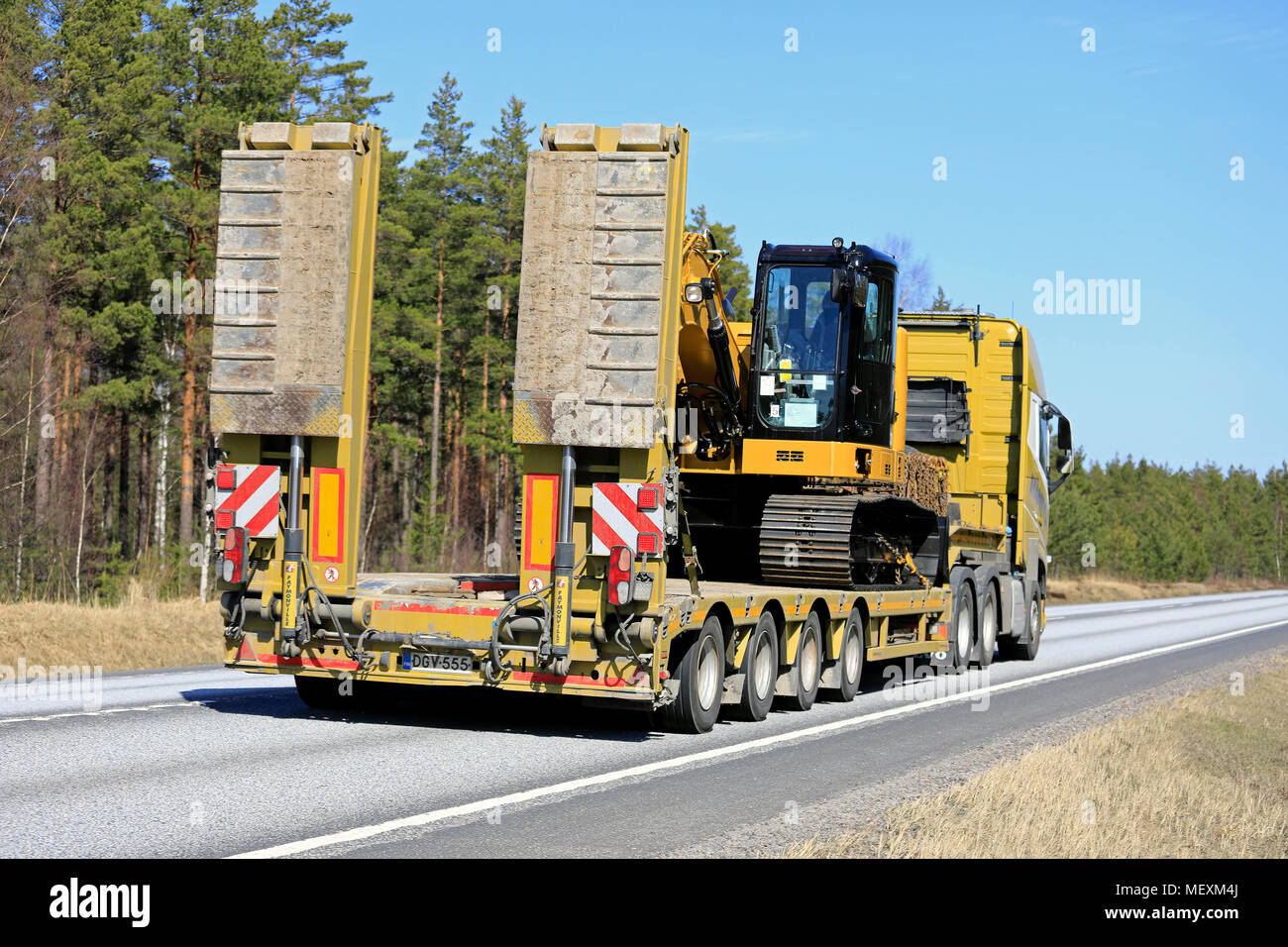 Rear view of Cat 315FL hydraulic excavator road transport by Volvo FH 500 truck gooseneck trailer on a clear day of spring in Raasepori, Finland - Apr Stock Photo