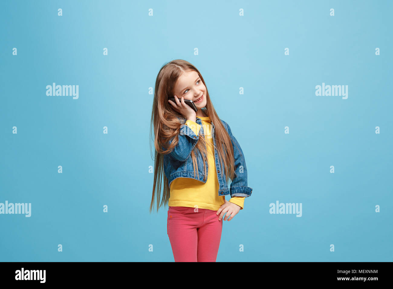 The happy teen girl standing and smiling against blue background Stock ...