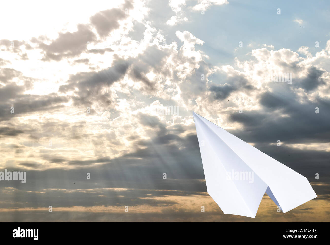 White paper airplane in a blue sky with clouds. The message symbol in ...