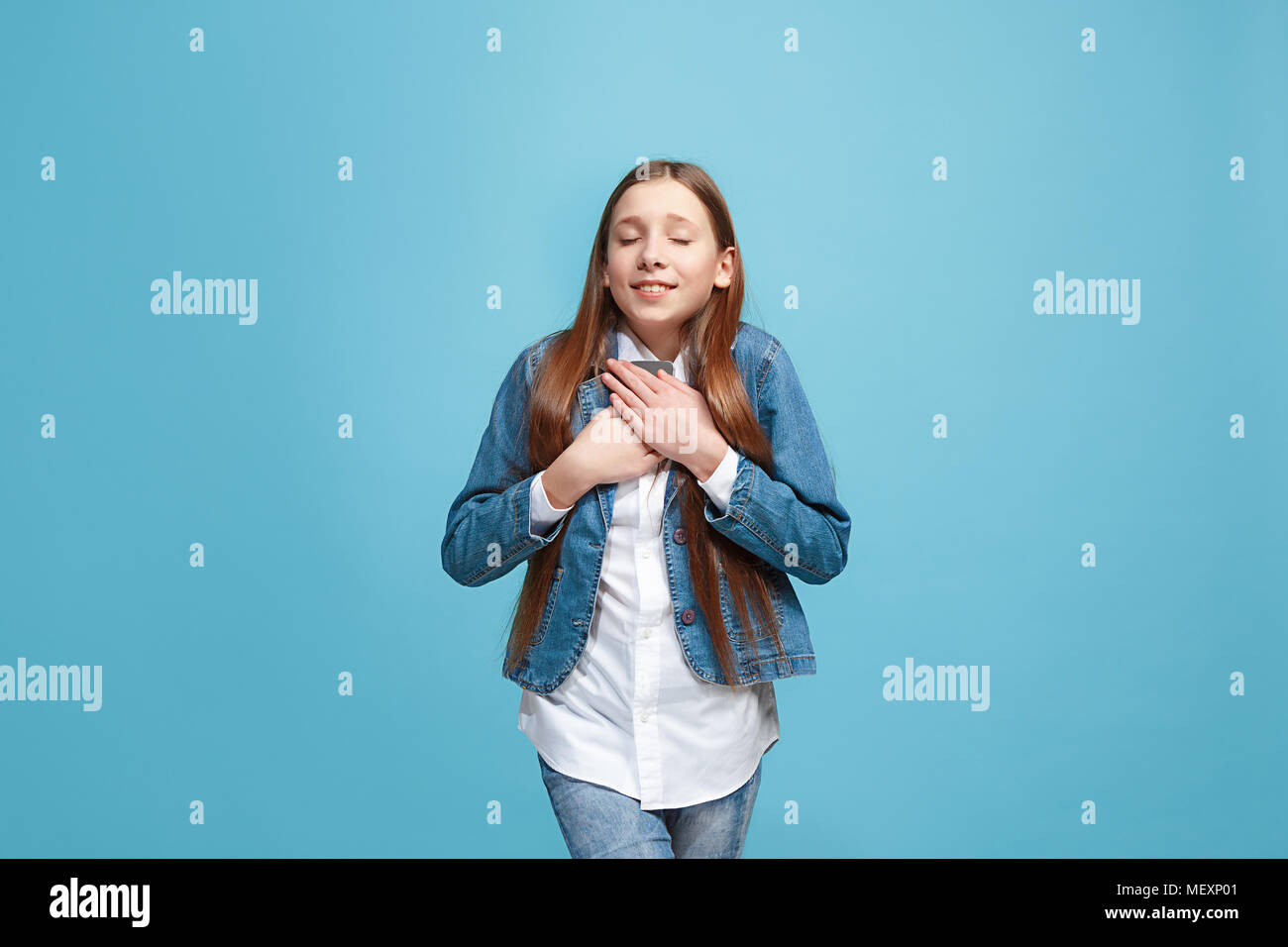 The happy teen girl standing and smiling against blue background Stock ...
