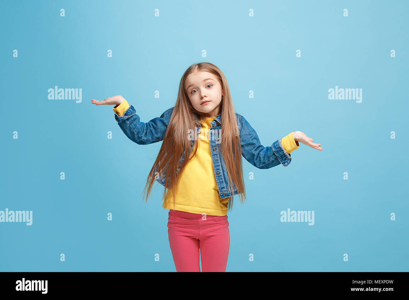 Beautiful teen girl looking suprised and bewildered isolated on blue Stock Photo