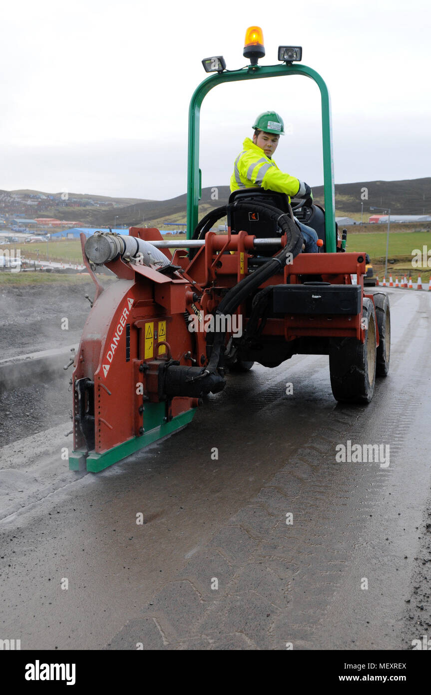 Track being cut in road by a saw so broadband cable can be laid Stock Photo