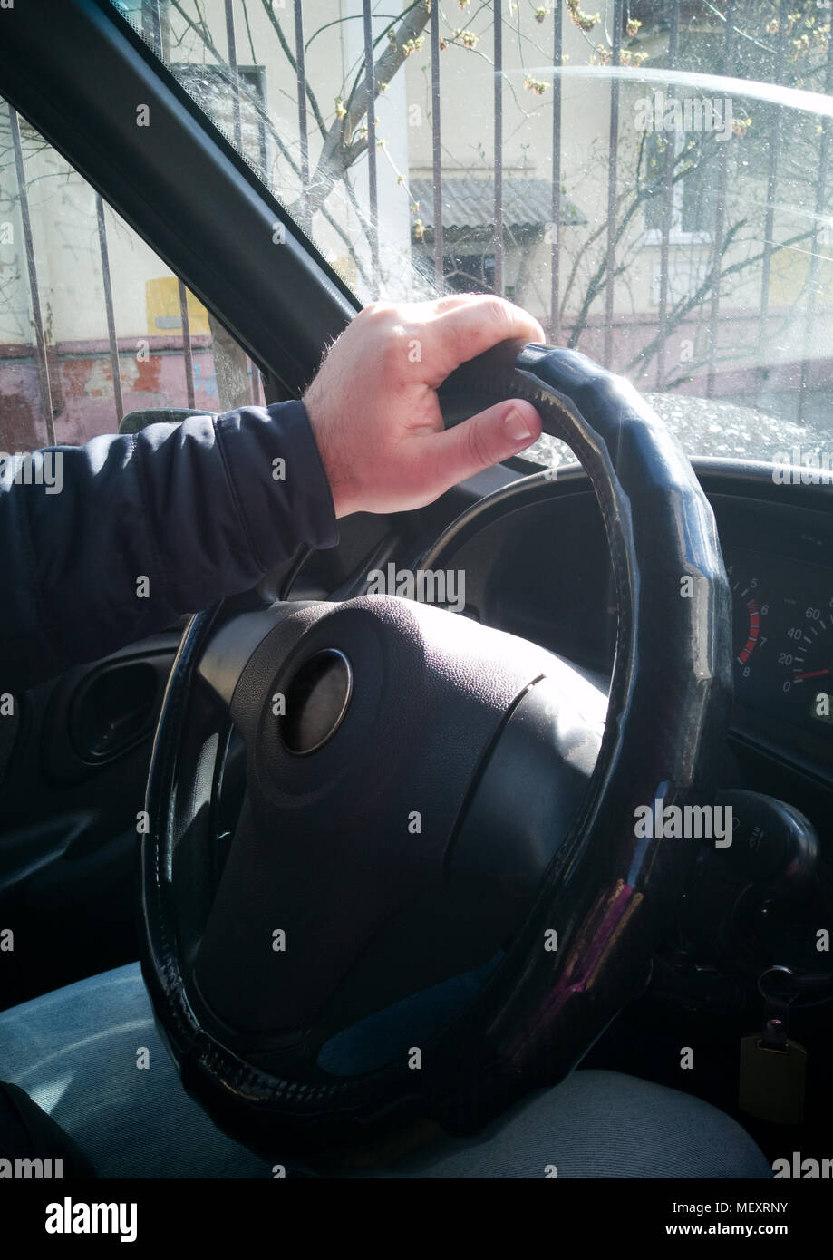 Close up. Hands of a man holding a steering wheel while driving a car