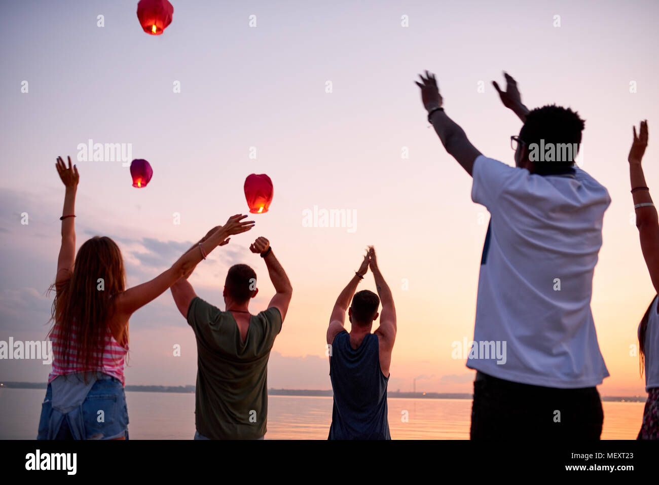 Excited young people saying goodbye to flying sky lanterns Stock Photo