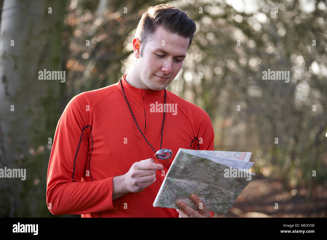 Man Orienteering In Woodlands With Map And Compass Stock Photo