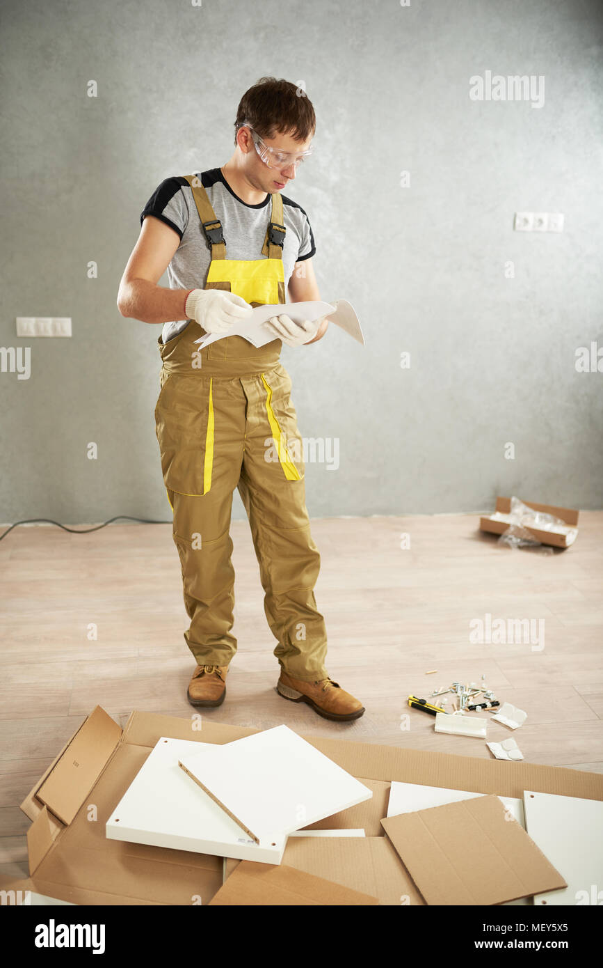 Worker checking instruction before furniture installation. Professional home help theme. Stock Photo