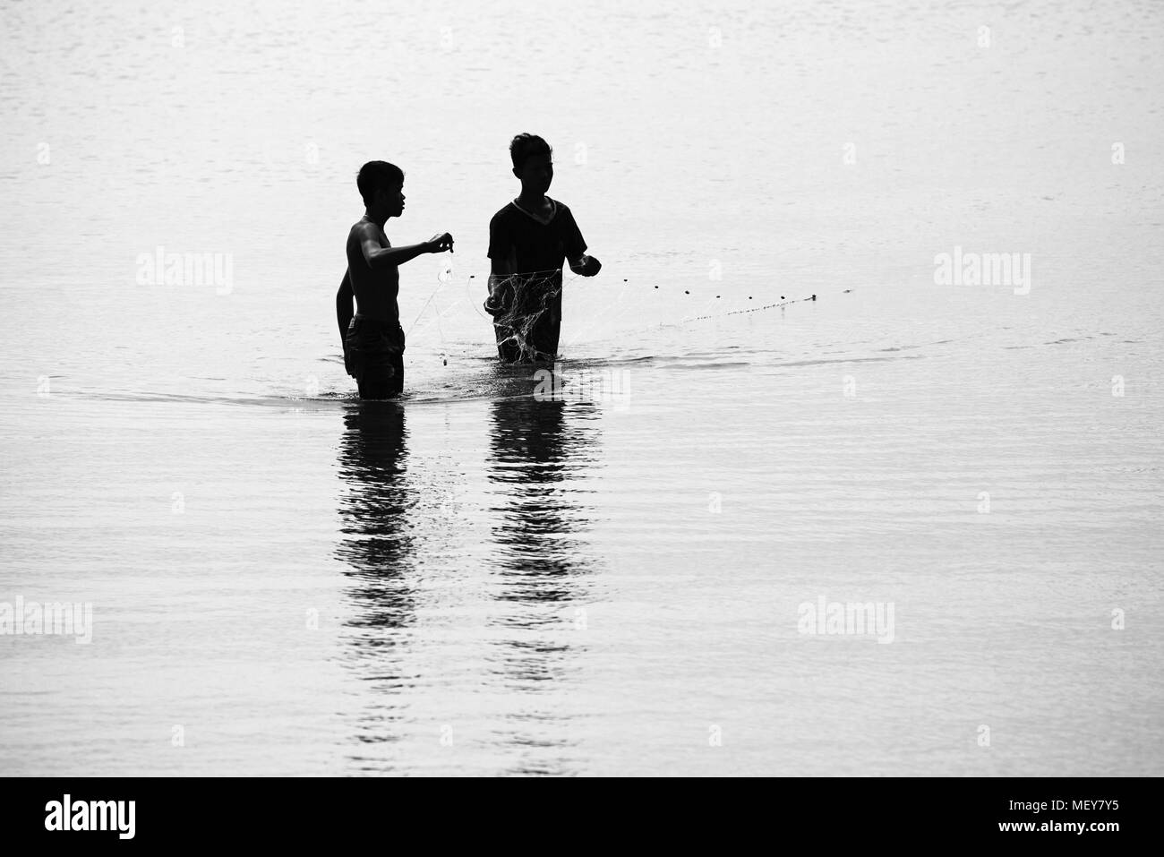 Silhouette of boys fishing on the beach Stock Photo
