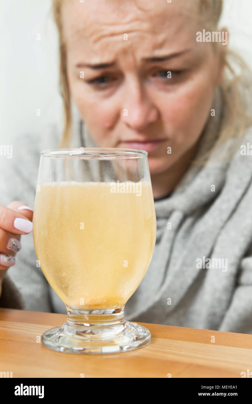 Young woman throws a tablet into a glass of water. Young woman with