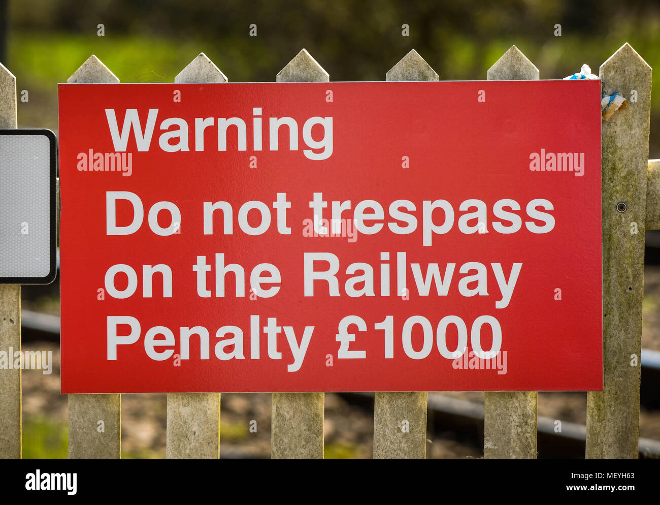 Red sign warning people not to trespass on a railway line at an unmanned level crossing Stock Photo