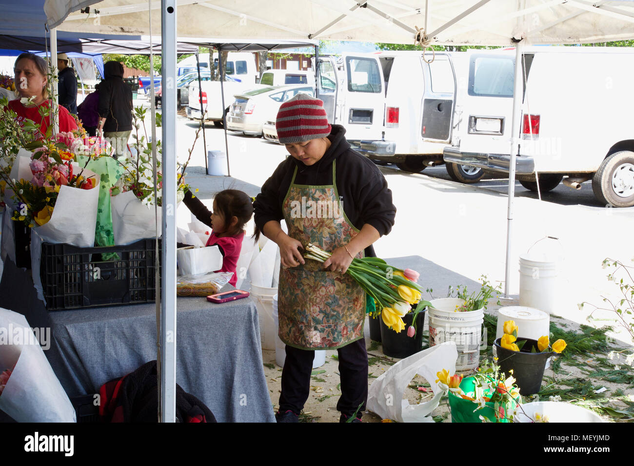 Woman making flower arrangements with young girl helping at the Piedmont Triad Farmers Market on 04212018 Stock Photo