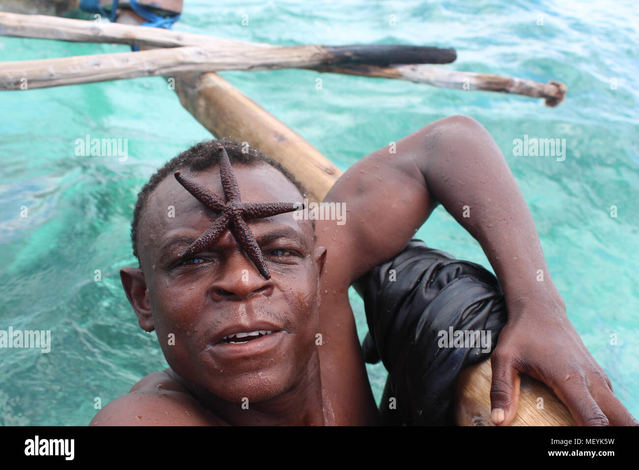 African man with starfish on face, Zanzibar, Tanzania Stock Photo