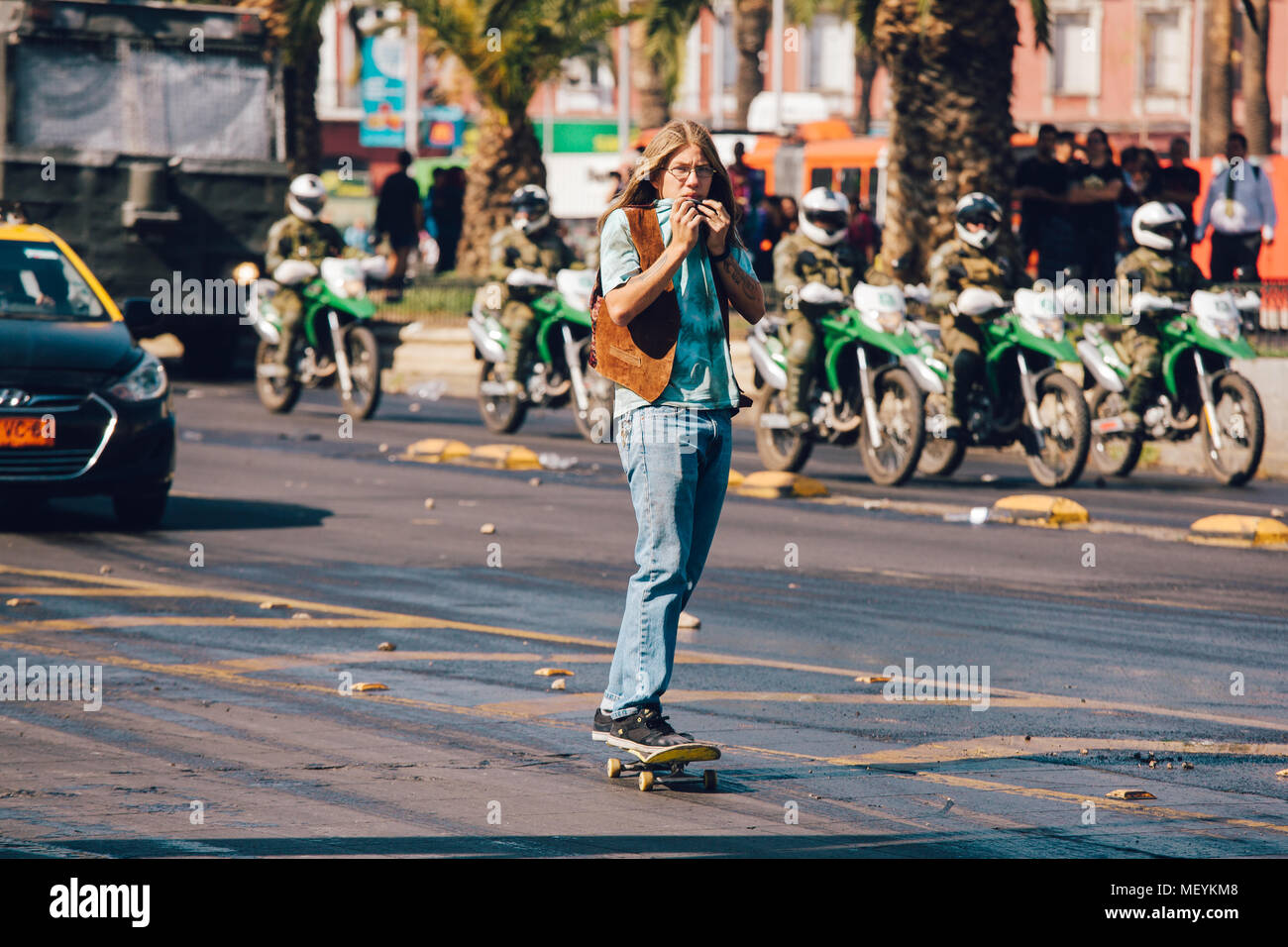 Santiago, Chile - April 19, 2018: skater is affected by tear gas during a demonstration demanding an end to the Profit in the Education. Stock Photo