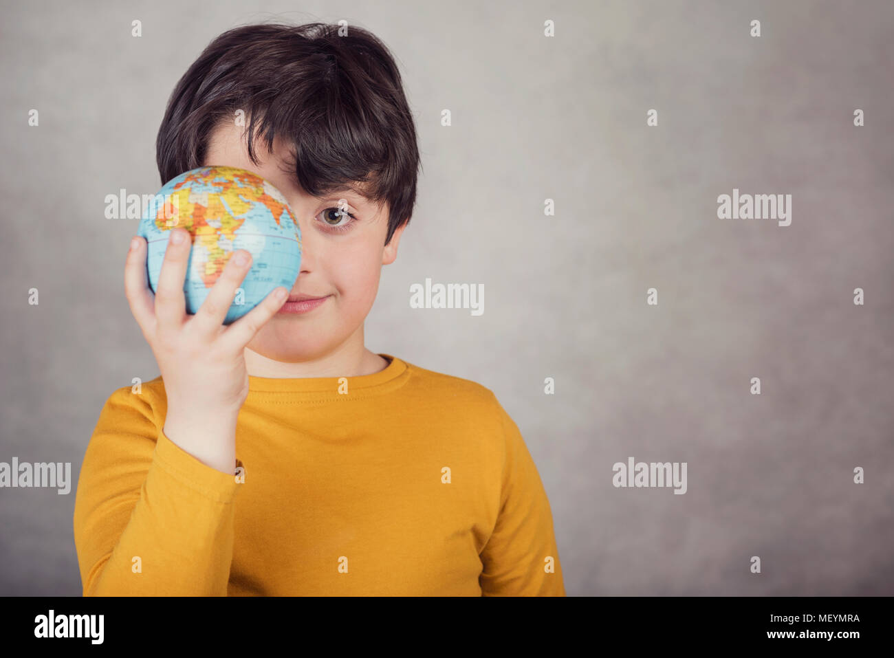 smiling boy with a earth globe covering his eye Stock Photo
