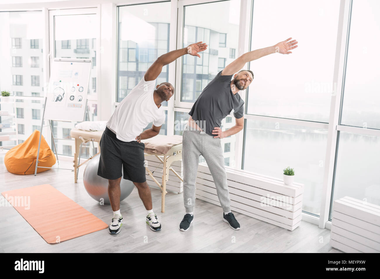 Positive sporty men doing physical activities Stock Photo