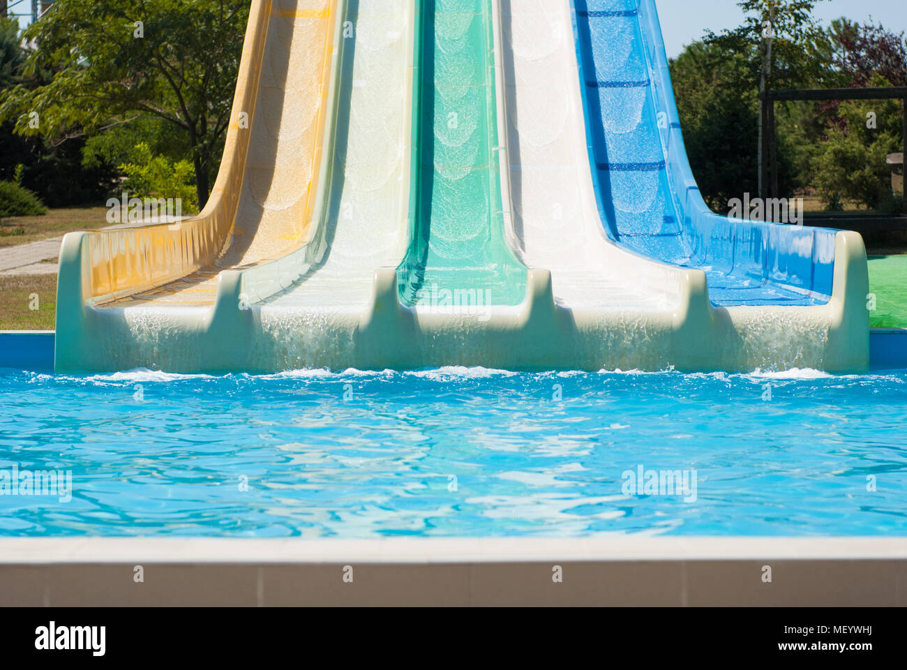 Water park with colorful water slides and blue swimming pool in summer sunny day Stock Photo