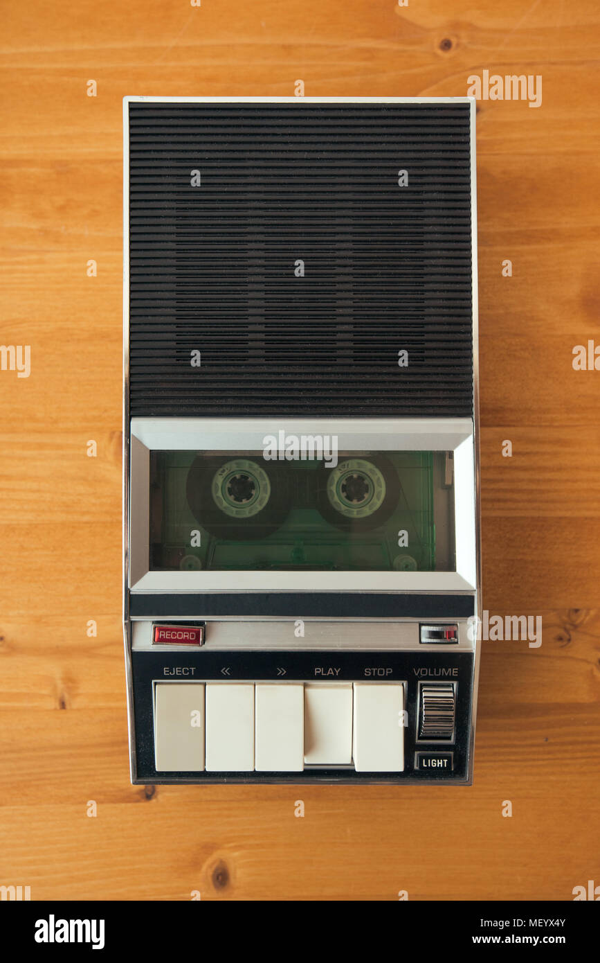 Audio cassette tape rolling in vintage player on the desk, top view. Police interrogation sound recording retro technology concept for 1970s, 80s and  Stock Photo