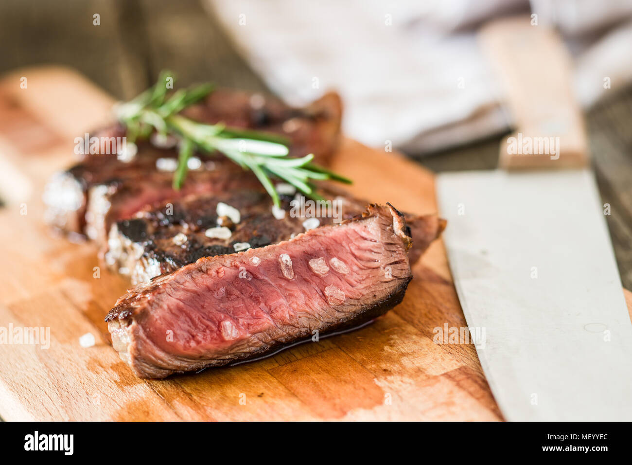 Sliced medium rare grilled steak on cutting board. Stock Photo