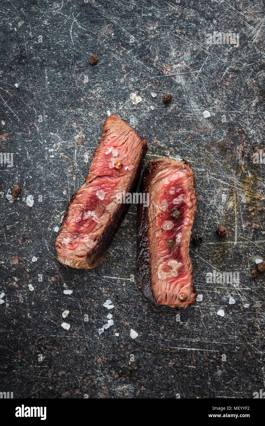 Sliced medium rare grilled steak on old kitchen table. Stock Photo
