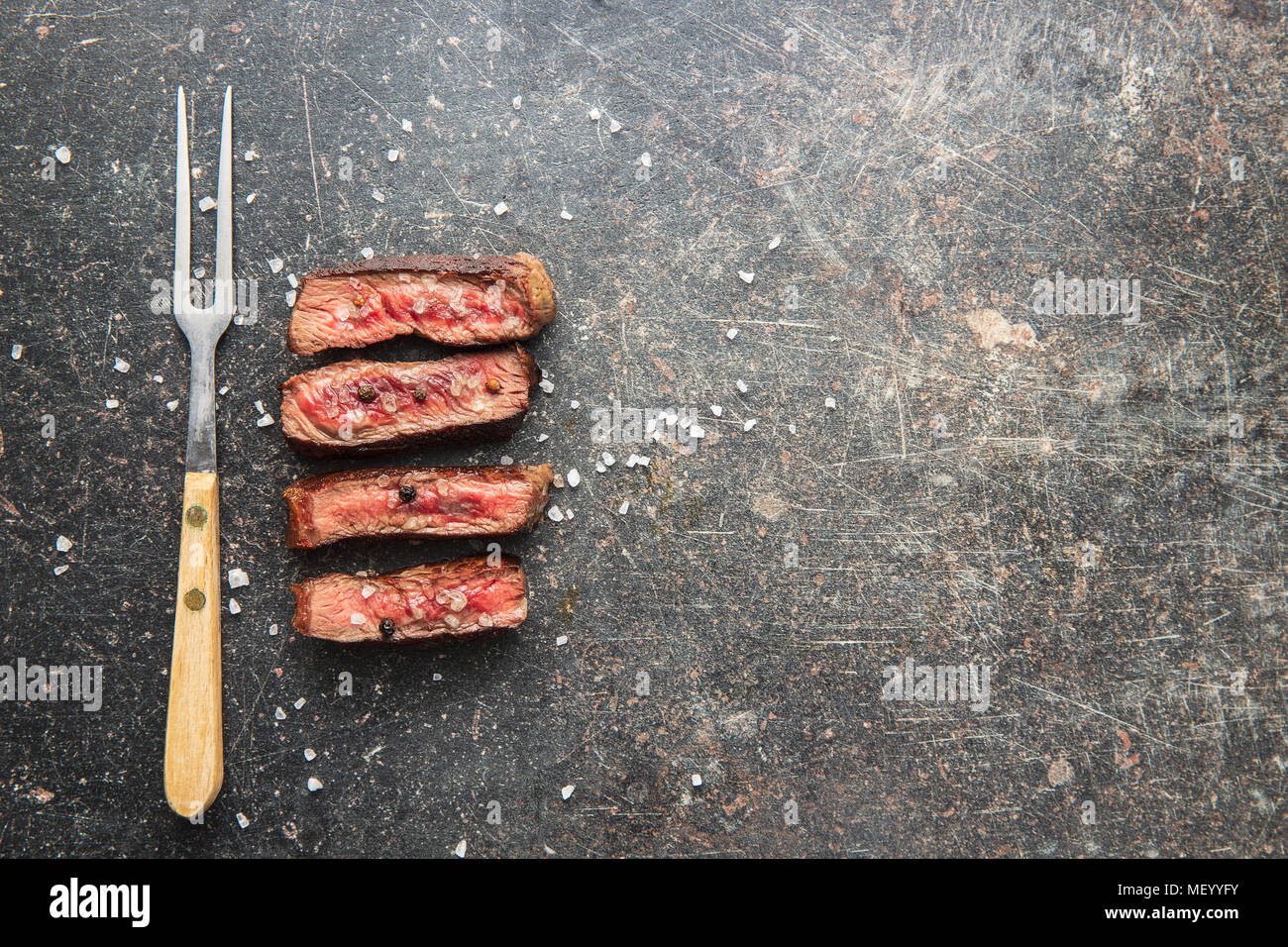 Sliced medium rare grilled steak on old kitchen table. Stock Photo