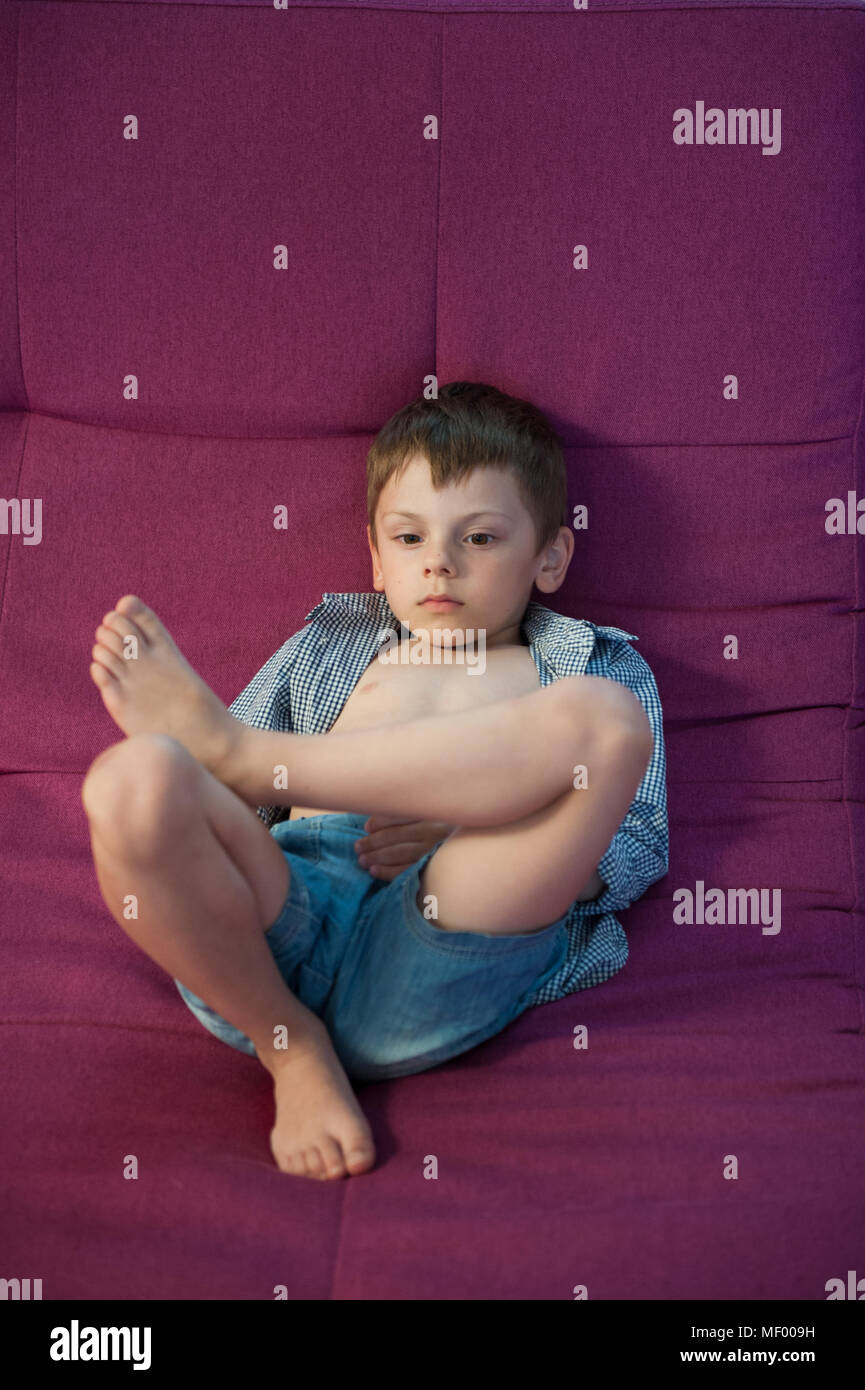 slacker cute little kid lying on couch resting watching TV Stock Photo