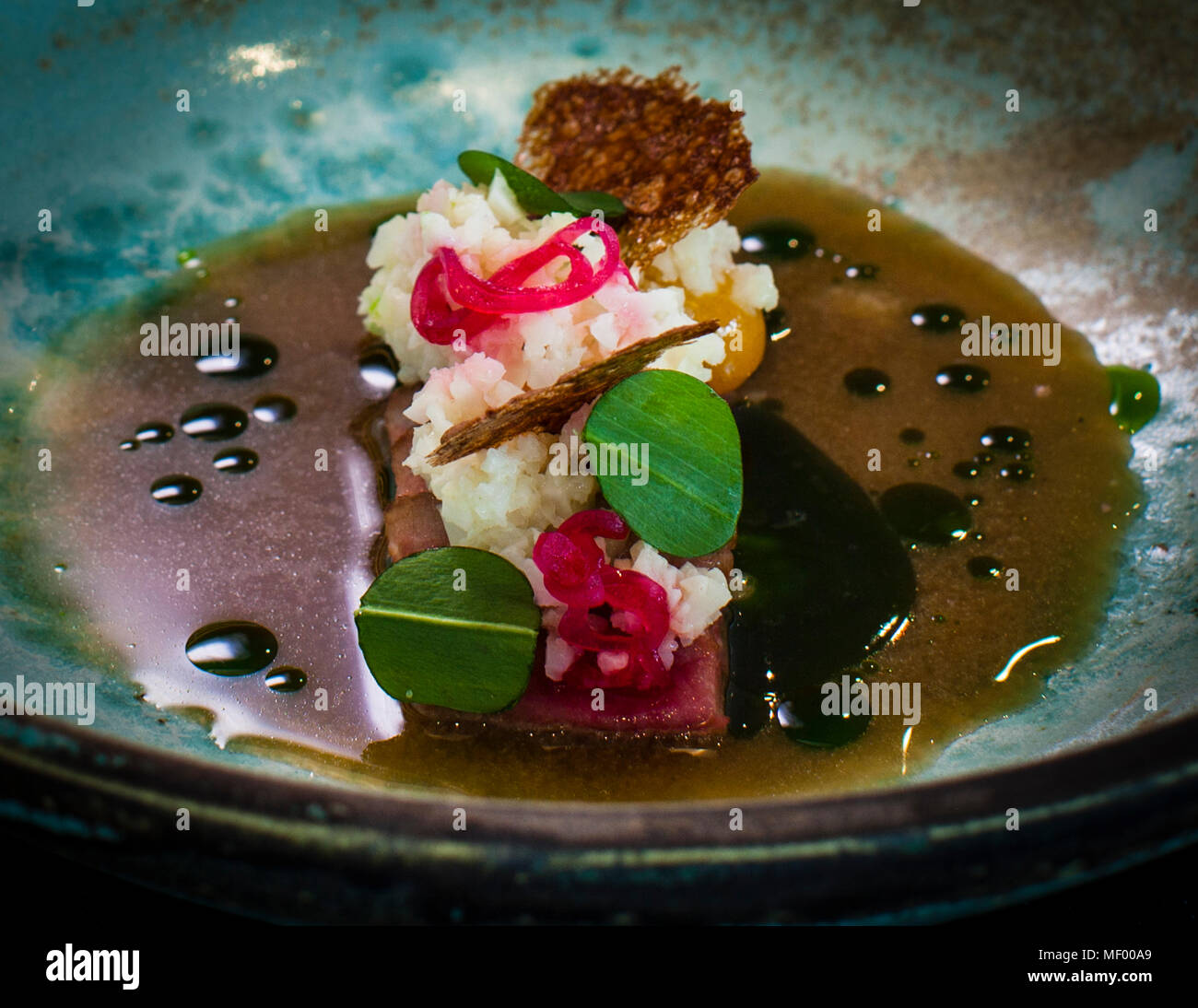 Miso Dish by German Michelin Star Chef Heiko Lacher. Restaurant Anima in Tuttlingen, Germany. Pork belly with cauliflower couscous in barley miso broth and wild garlic oil Stock Photo