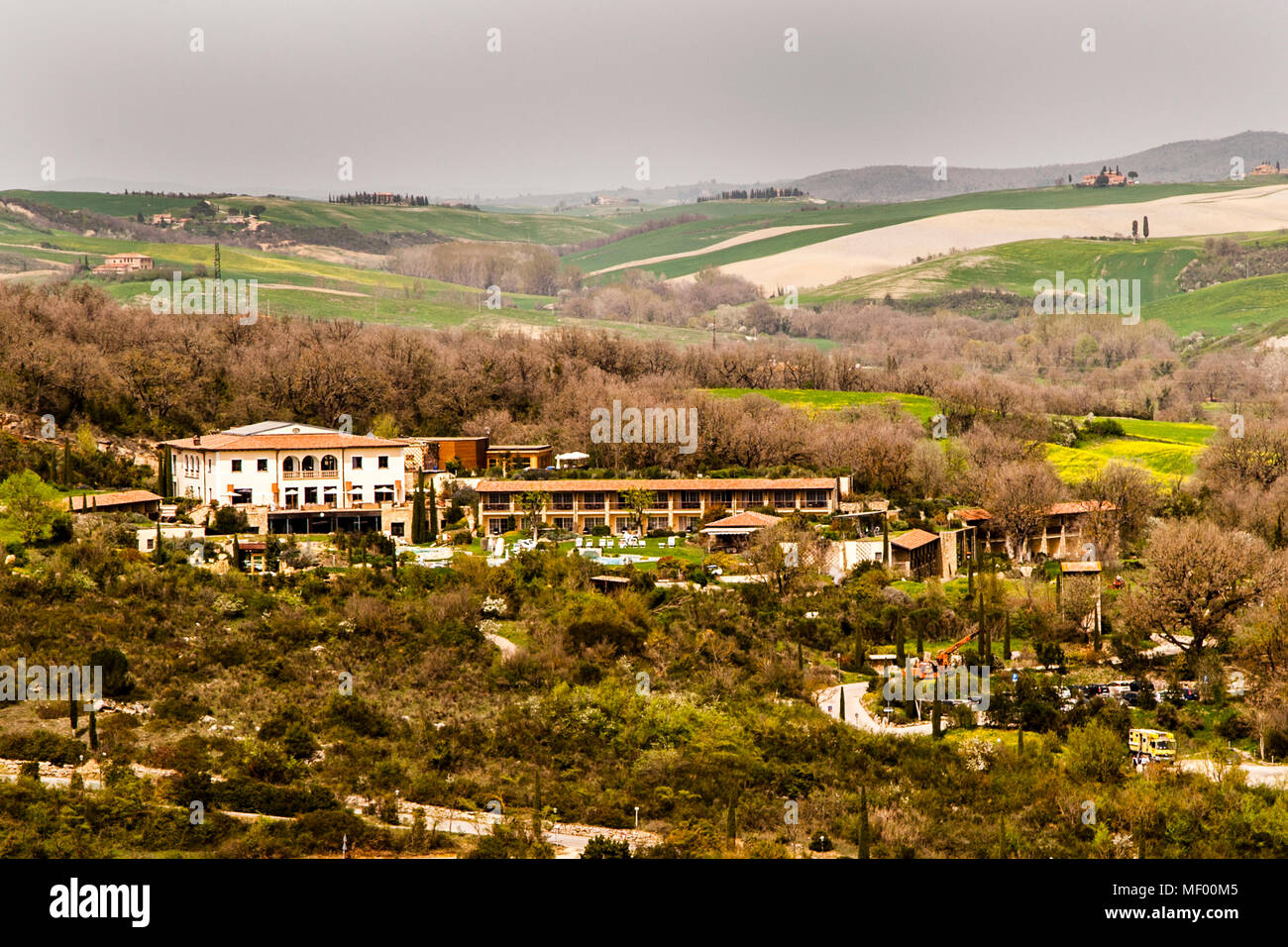 Tuscan landscape in spring, green fields, cypreses and olive trees, hiking in Tuscany, Val d'orcia Italy, UNESCO World Heritage. The Hotel dler Thermae blends unobtrusively into the landscape Stock Photo