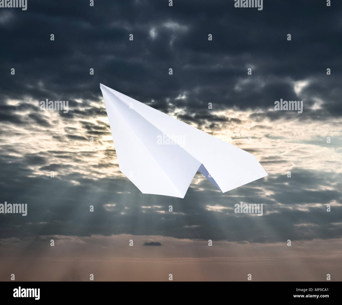 White paper airplane in a blue sky with clouds. The message symbol in ...