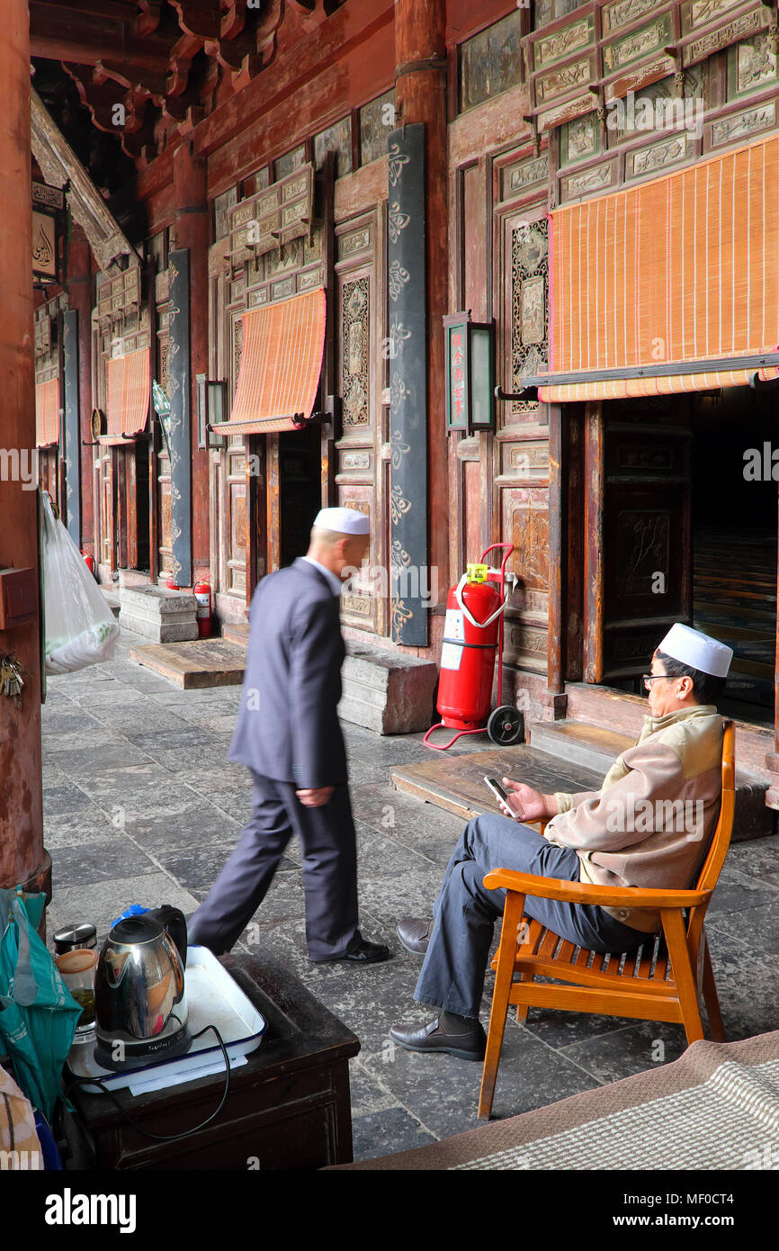 Custodian with mobile phone, entrance to the prayer hall, Great Mosque of Xi'an, Xi'an, Shaanxi Province, China Stock Photo