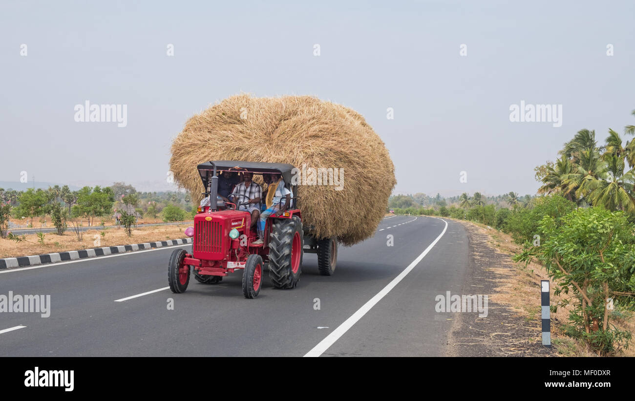 Sivaganga, India - March 11, 2018: Wide agricultural load together with a number of passengers being transported down a highway in Tamil Nadu Stock Photo