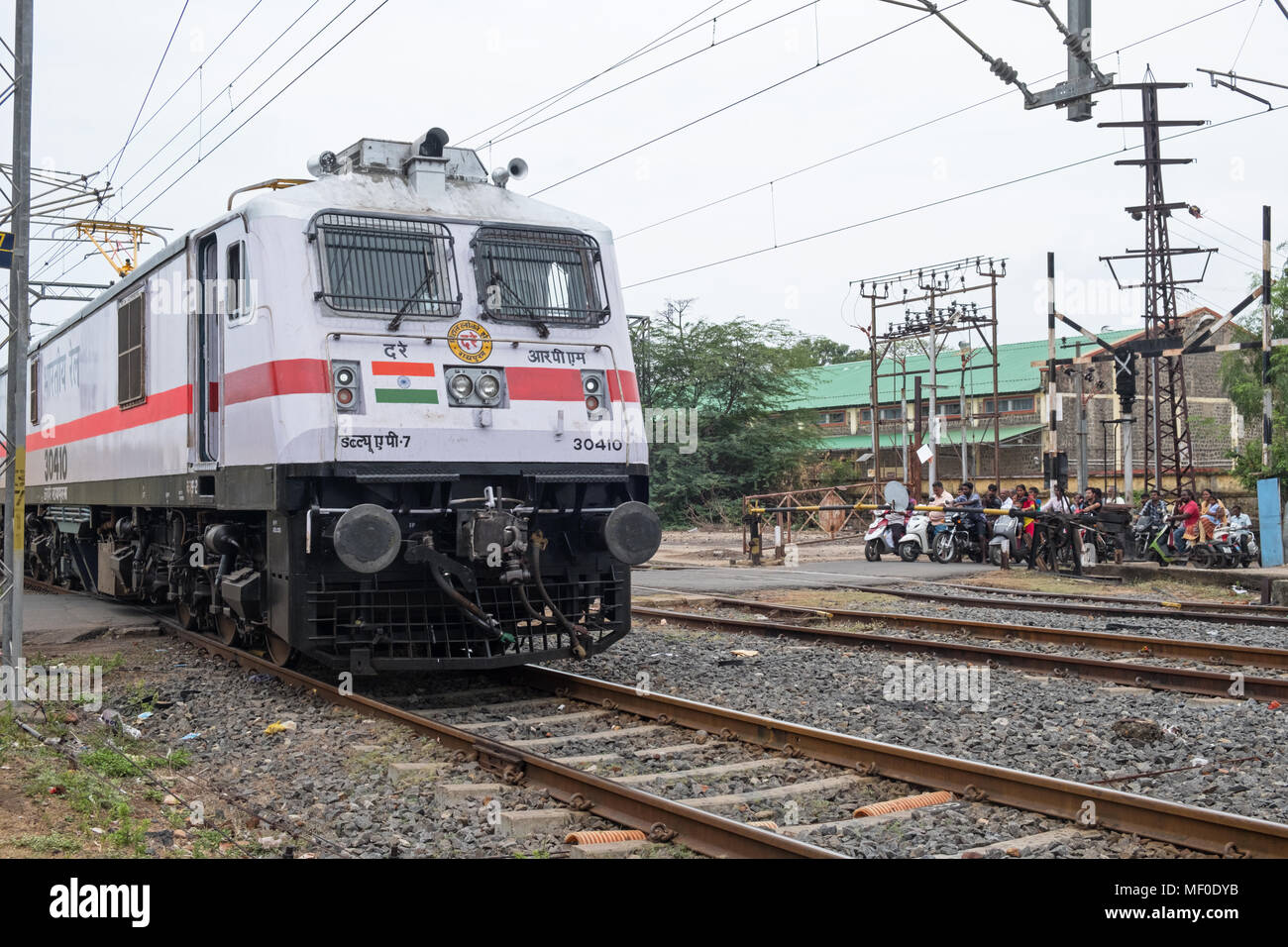 Pondicherry, India - March 17, 2018: A locomotive at the front of a passenger train passing over a level crossing outside the main station Stock Photo